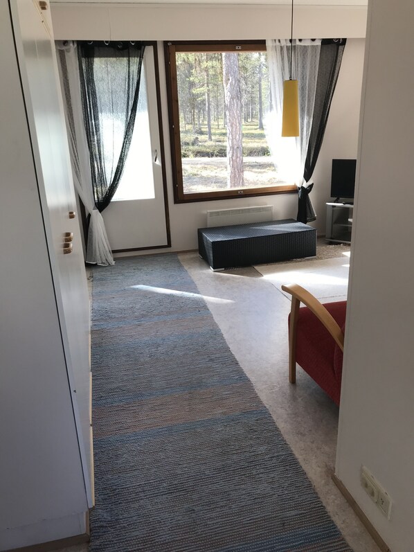 A room with a large window, a bench, a TV, and a door.