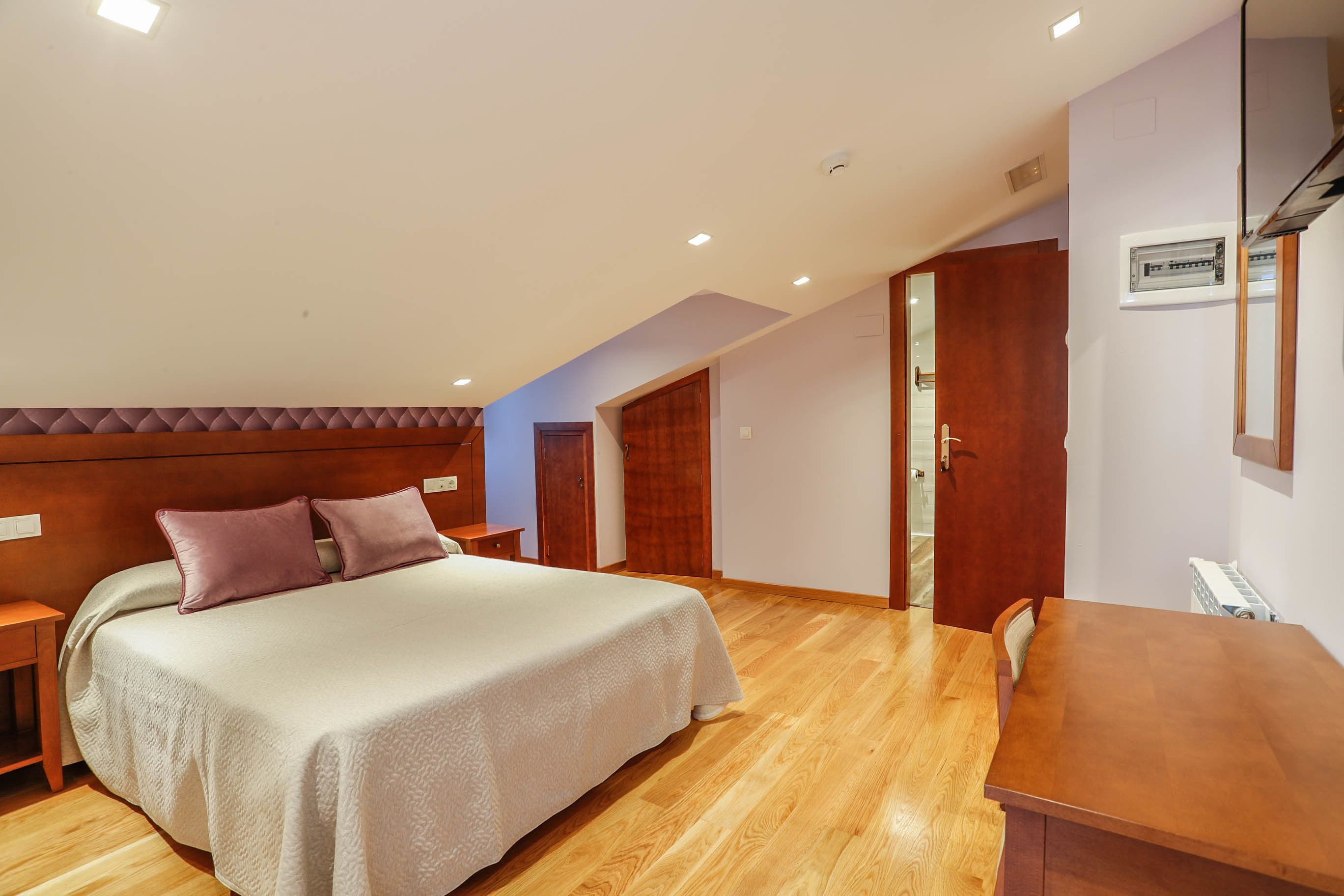 Un dormitorio con cama, mesitas de noche, un escritorio de madera y un armario empotrado.