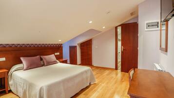 A bedroom with a bed, bedside tables, a wooden desk, and a built-in wardrobe.