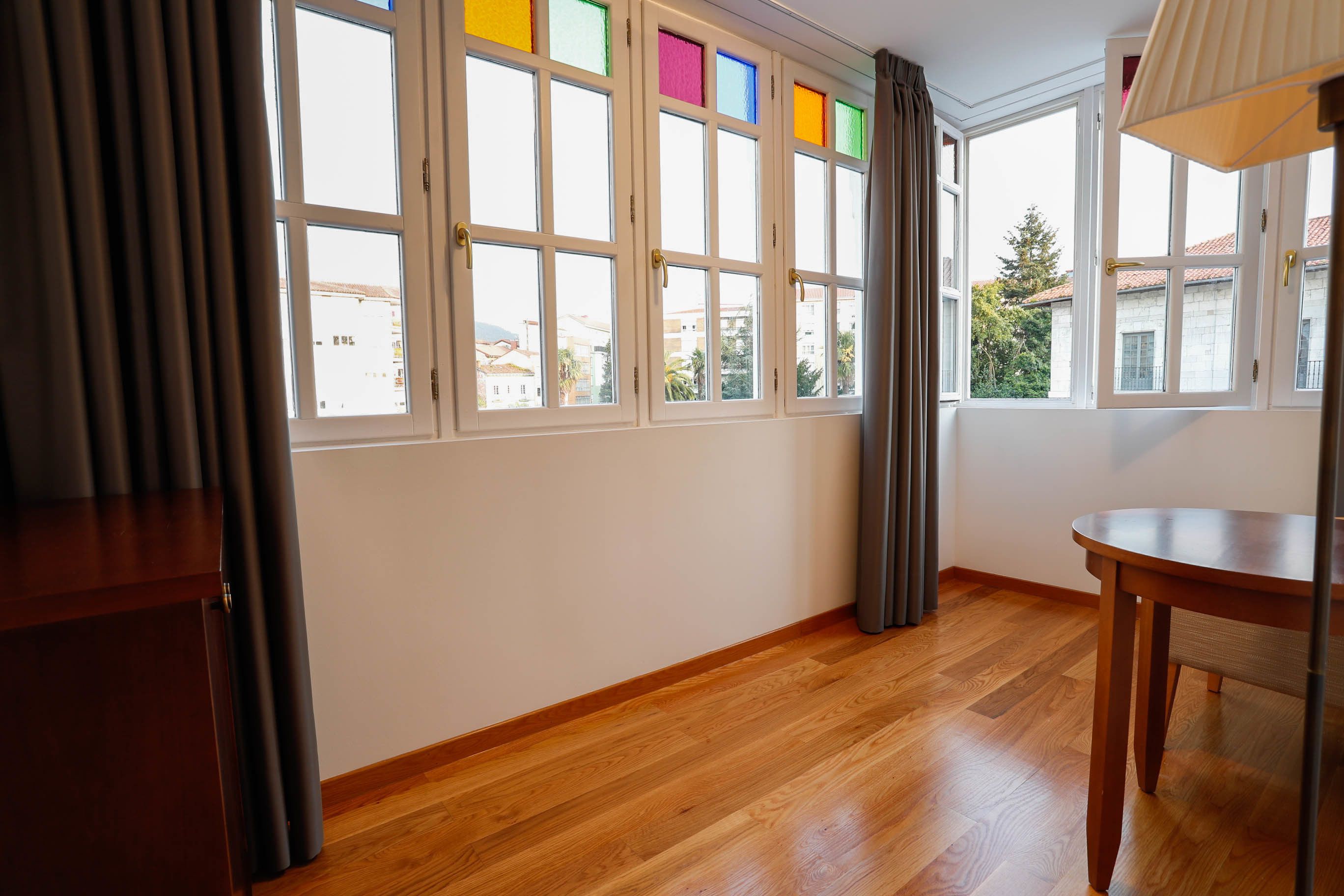 Una habitación con ventanas amplias, piso de madera y una mesa.