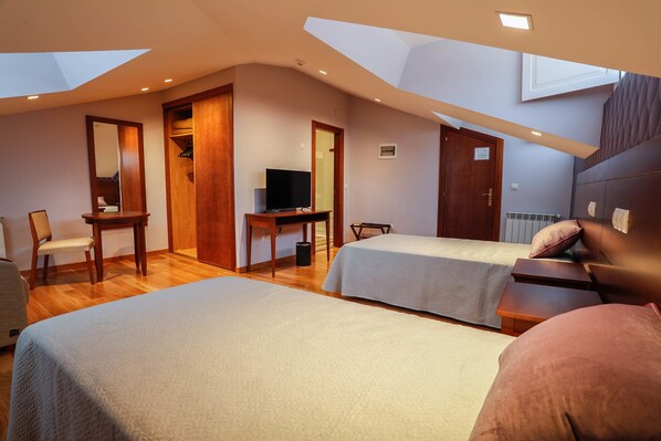 A bedroom with two beds, a desk, a TV, and a wardrobe. - Hotel Rey Silo (Pravia)