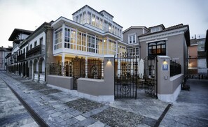 A hotel with a large entrance, a covered outdoor seating area, and a gated courtyard. - Hotel Rey Silo (Pravia)