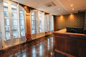 Ein Hotel-Rezeptionsbereich mit einem Holzbüro, einem Feuerlöscher und einer Wand mit Musterdesign.