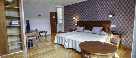 Een hotelkamer met een bed, nachtkastjes, een bureau, een stoel, een houten vloer en een kledingkast.