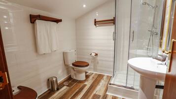 Un baño con inodoro, bidé y zona de ducha con mampara de cristal.