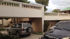 Un bâtiment à deux étages avec un garage où sont stationnés un VUS argenté et un VUS noir.