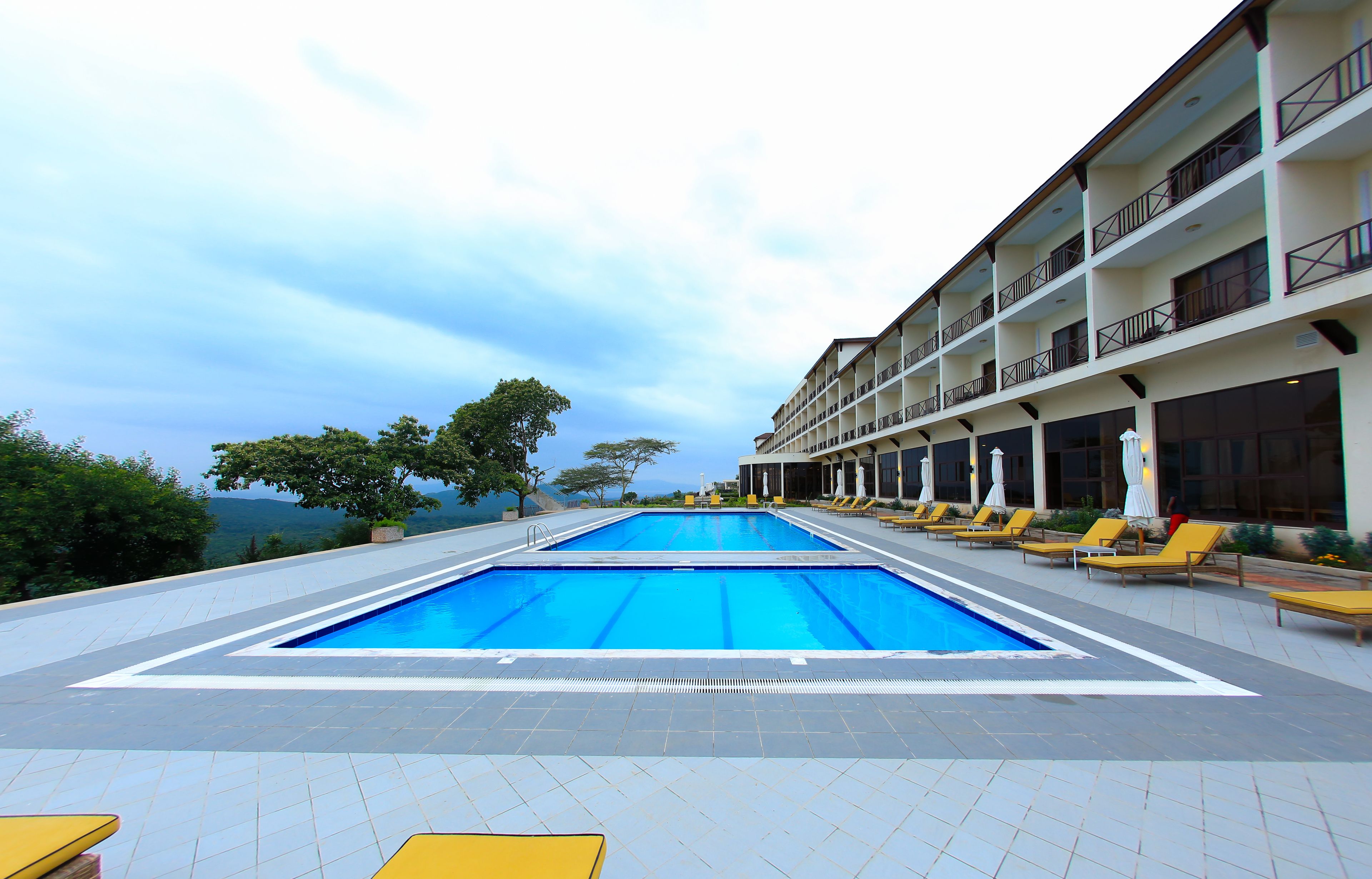 Una piscina con sillas de descanso y un edificio con balcones.