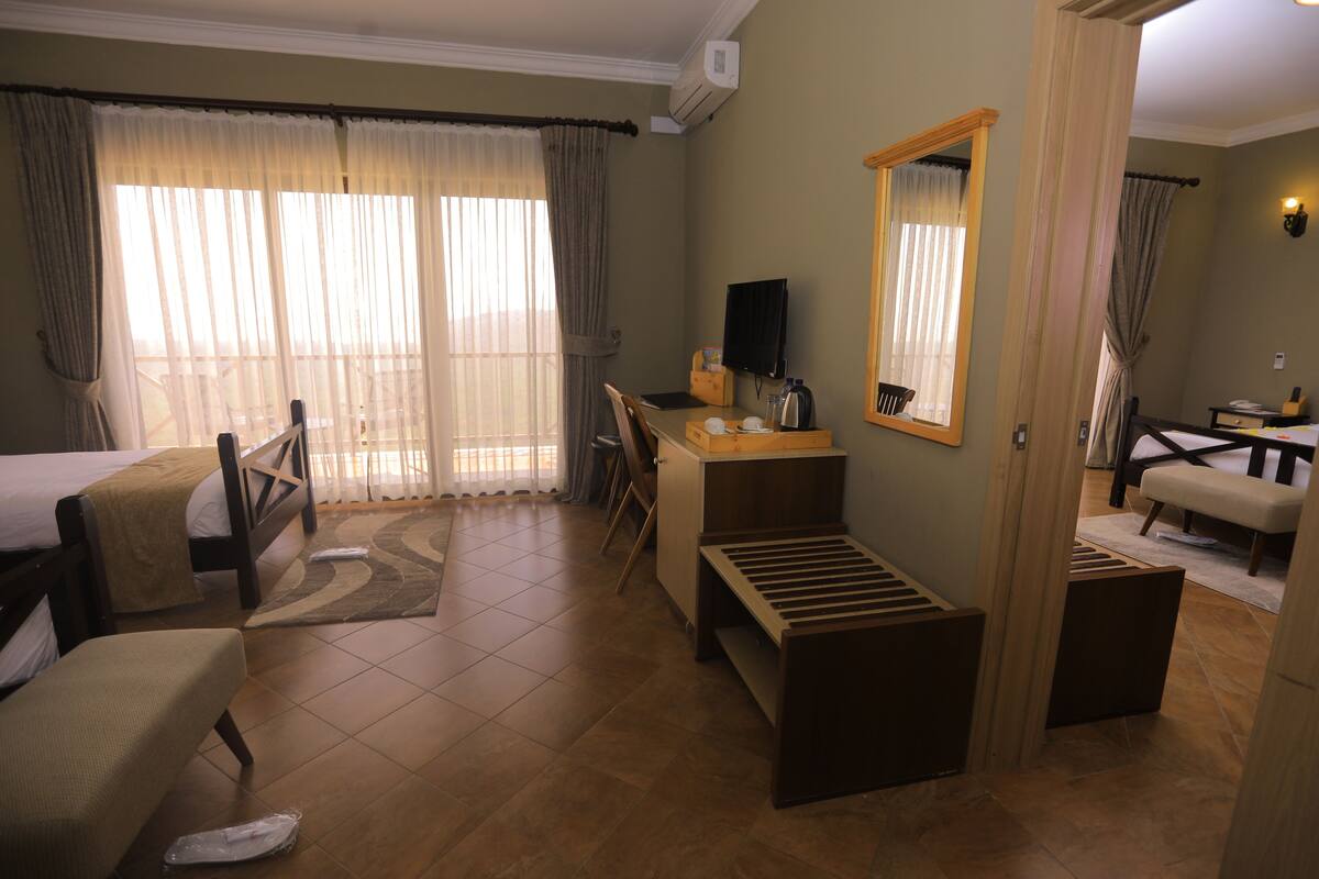 A hotel room with a bed, desk, chair, and a large mirror.