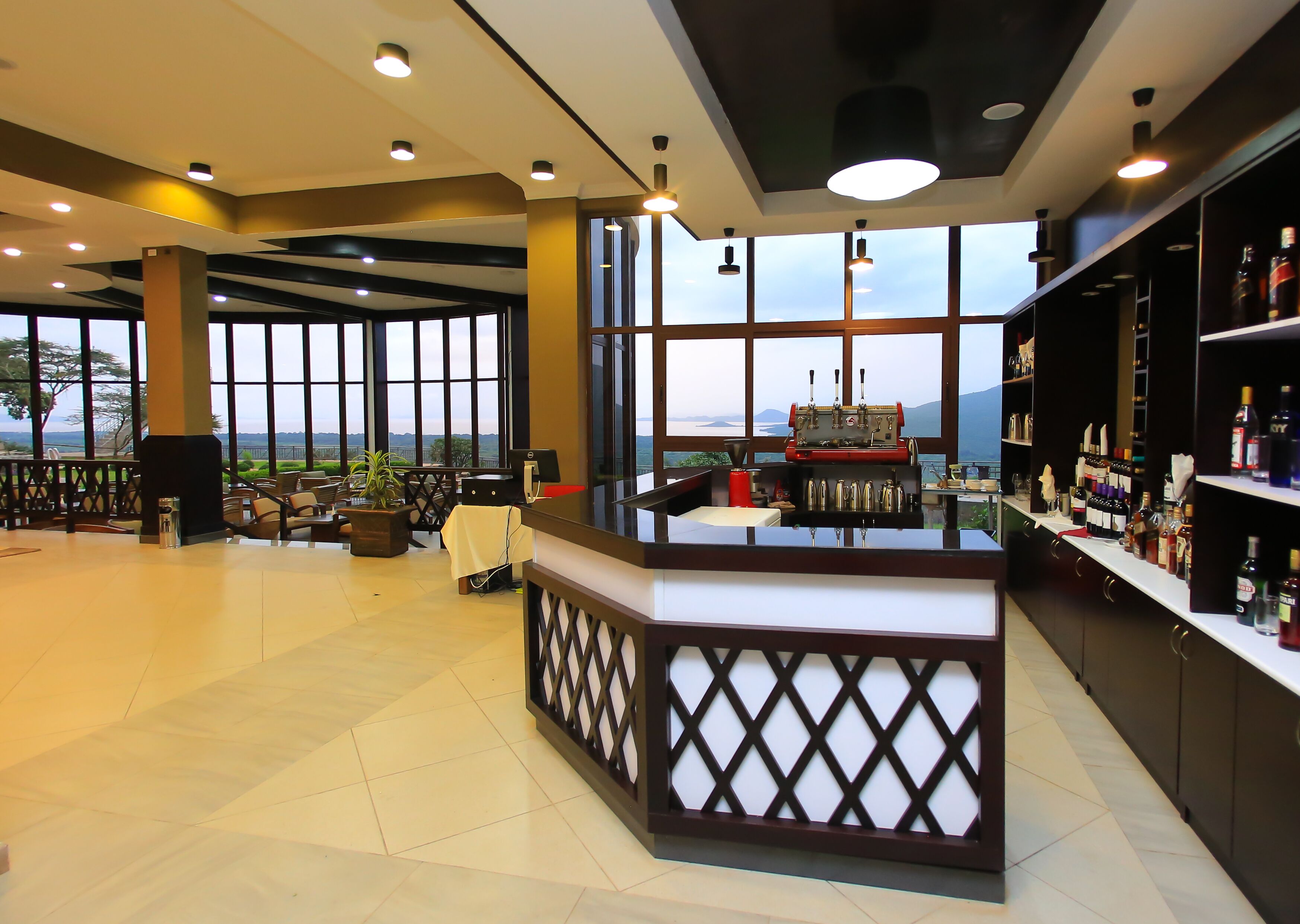 Uma área de bar moderna com máquina de café, assentos e vista para o exterior.