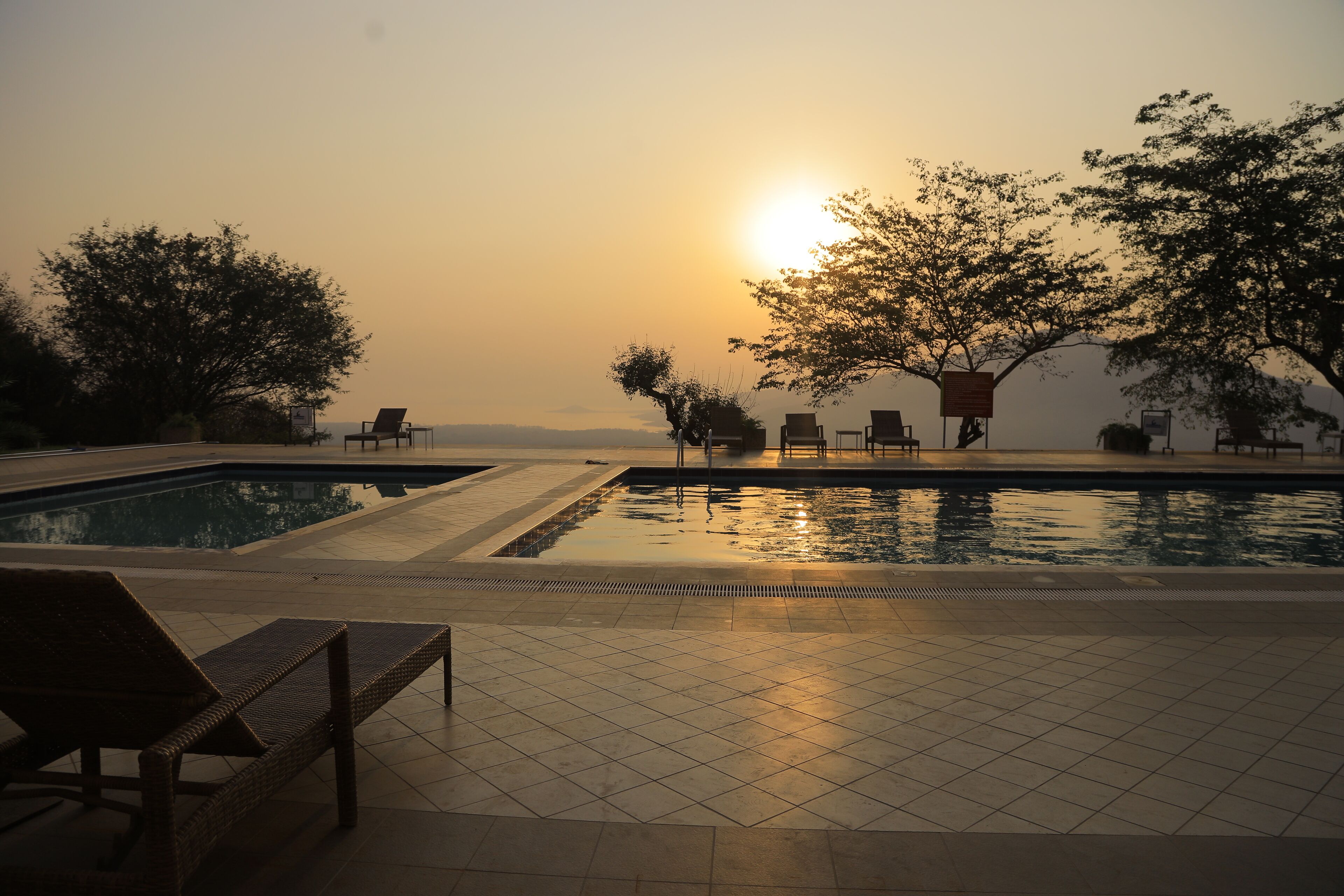 Ein Schwimmbecken mit Liegestühlen und Blick auf den Sonnenuntergang.