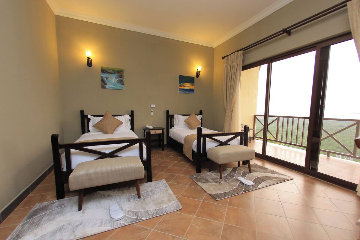A hotel room with two beds, a balcony, and a view of the landscape.