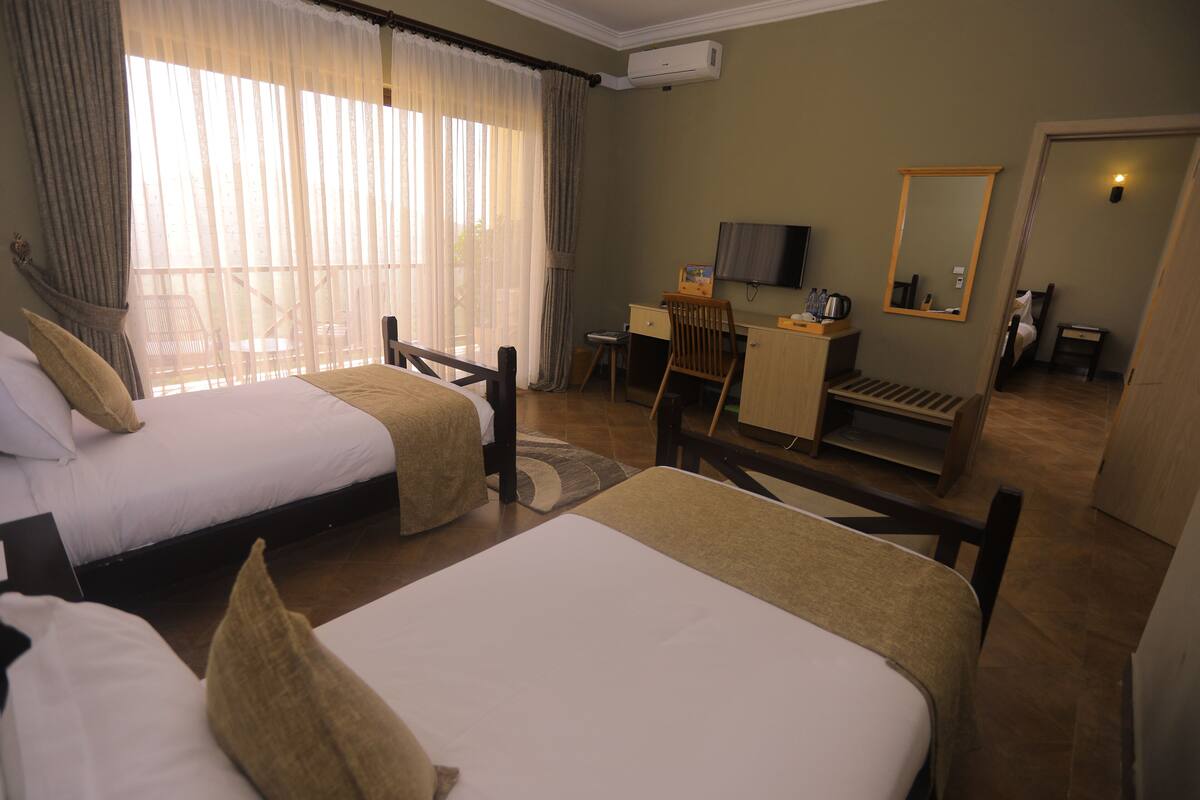 A hotel room with two beds, a desk, a television, and a mirror.