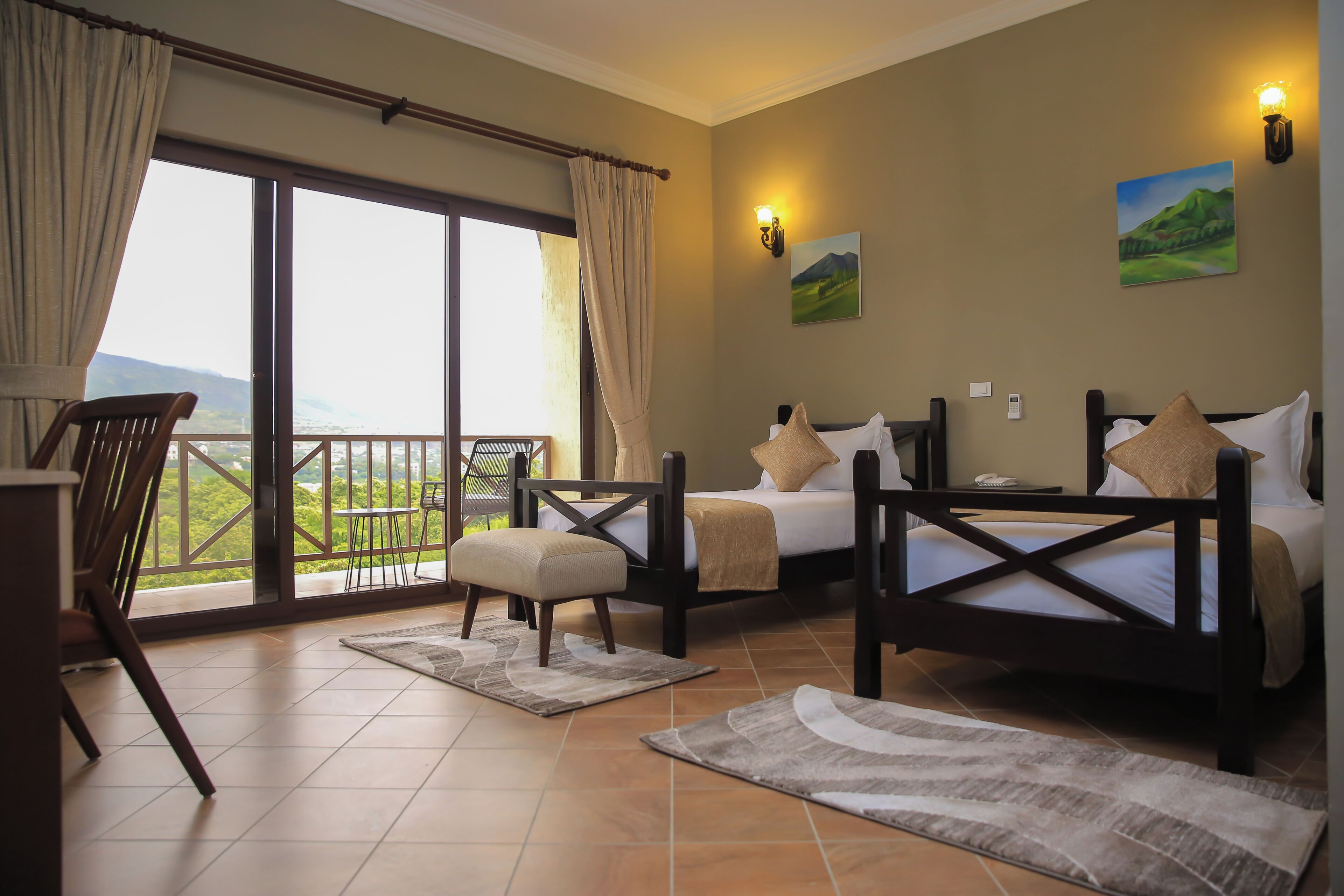 A hotel room with two beds, a balcony with a view, and a dining area.