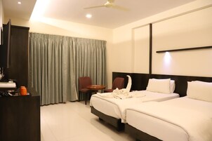 Una habitación de hotel con cama, escritorio, silla y televisor.