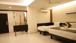 Habitación de hotel con cama, escritorio y silla. Se observa un equipo de aire acondicionado en la pared y un ventilador de techo.