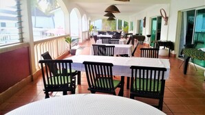 Un restaurante con mesas al aire libre, manteles blancos y sillas negras.