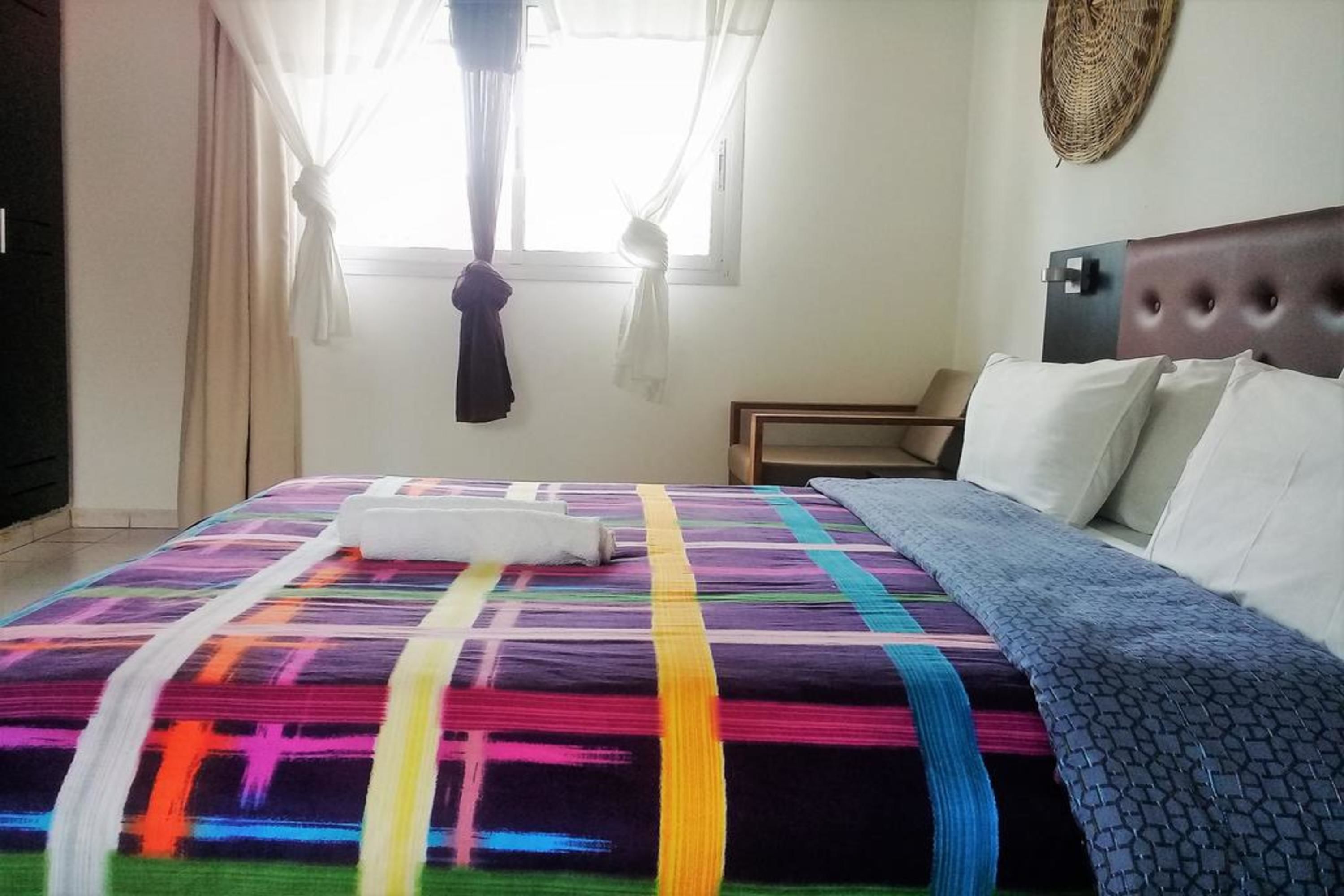 Una habitación de hotel con una cama, una ventana con cortinas, un cabecero y un adorno en la pared.