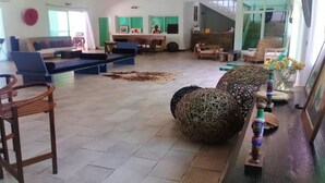 Un salón amplio con un conjunto de sofás, una mesa de centro y una mesa de comedor. Hay sillas y una alfombra en el suelo.