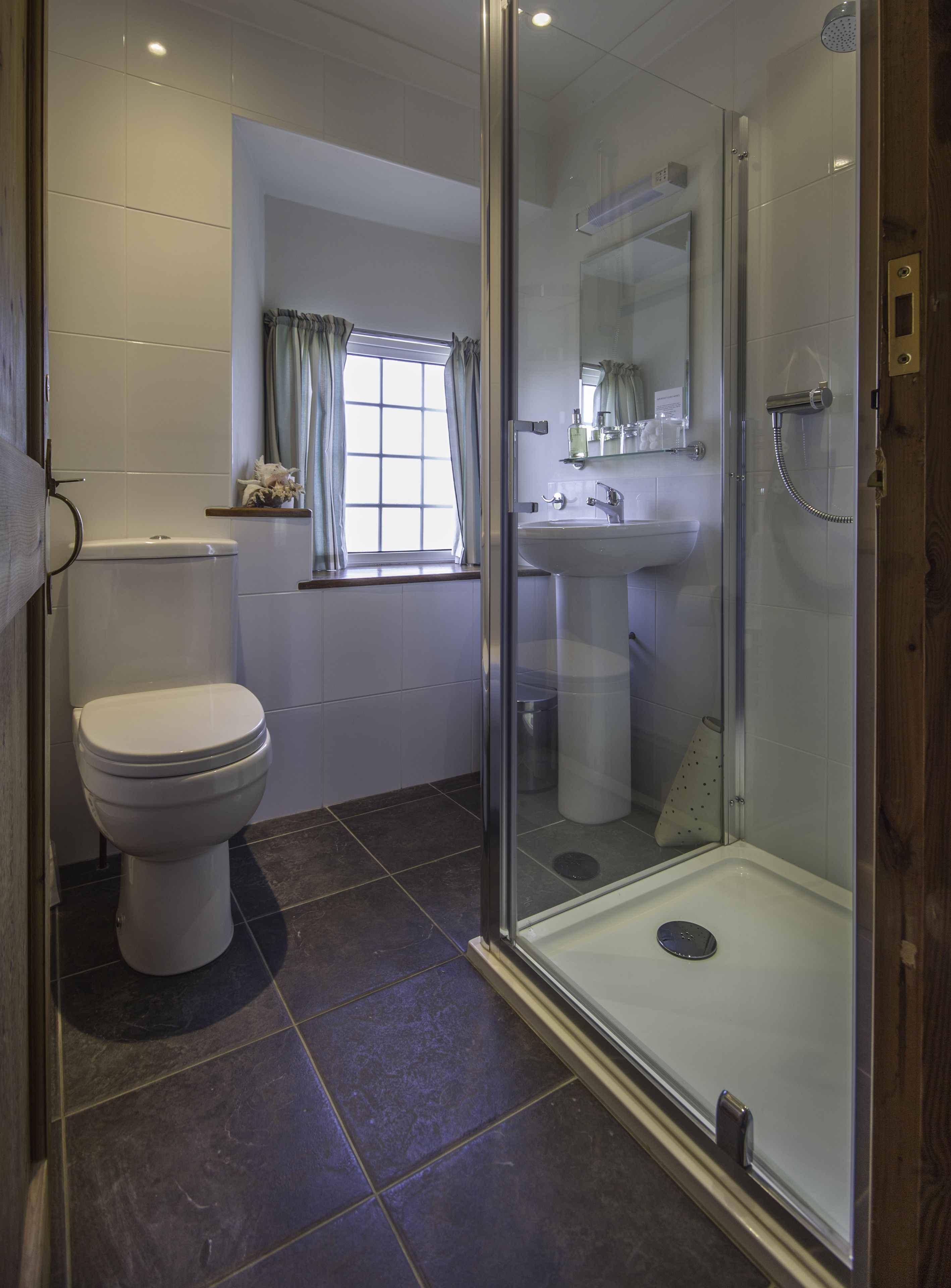 A modern bathroom with a toilet, sink, and glass-enclosed shower.