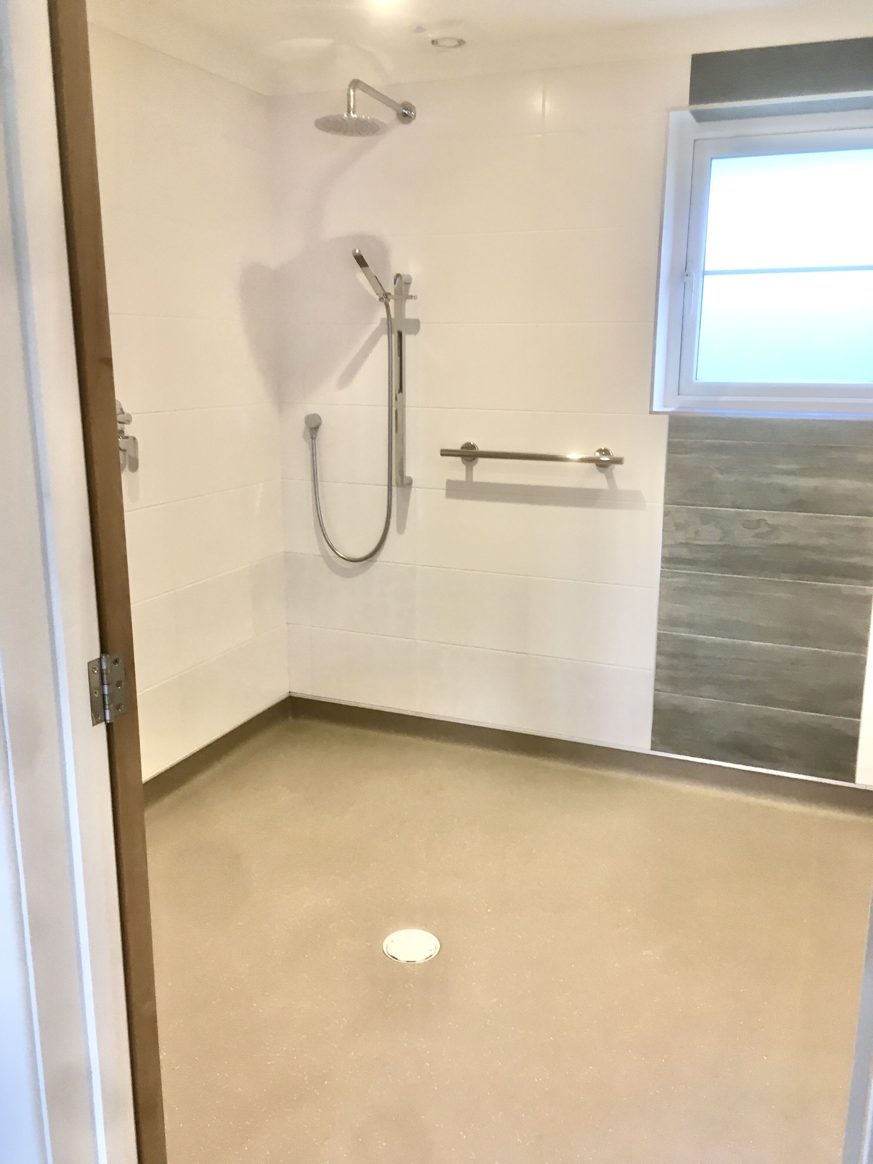 A modern bathroom with a shower, a towel rack, and a window.