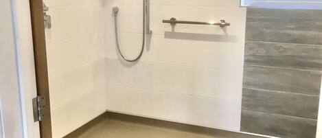 A modern bathroom with a shower, a towel rack, and a window.