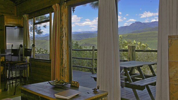A rustic wooden room with a large window overlooking a scenic landscape. - Treks Trips and Trails (Cathkin Park)