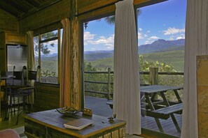 A rustic wooden room with a large window overlooking a scenic landscape. - Treks Trips and Trails (Cathkin Park)