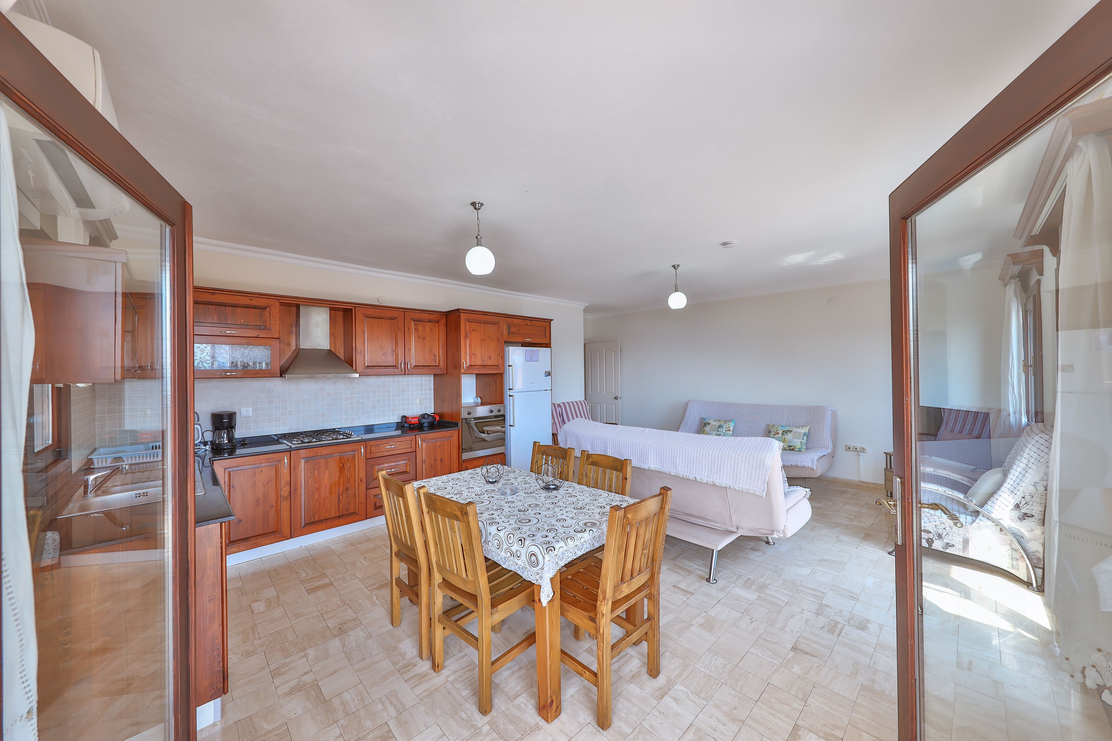 A compact kitchen with wooden cabinets, a dining table, and chairs.