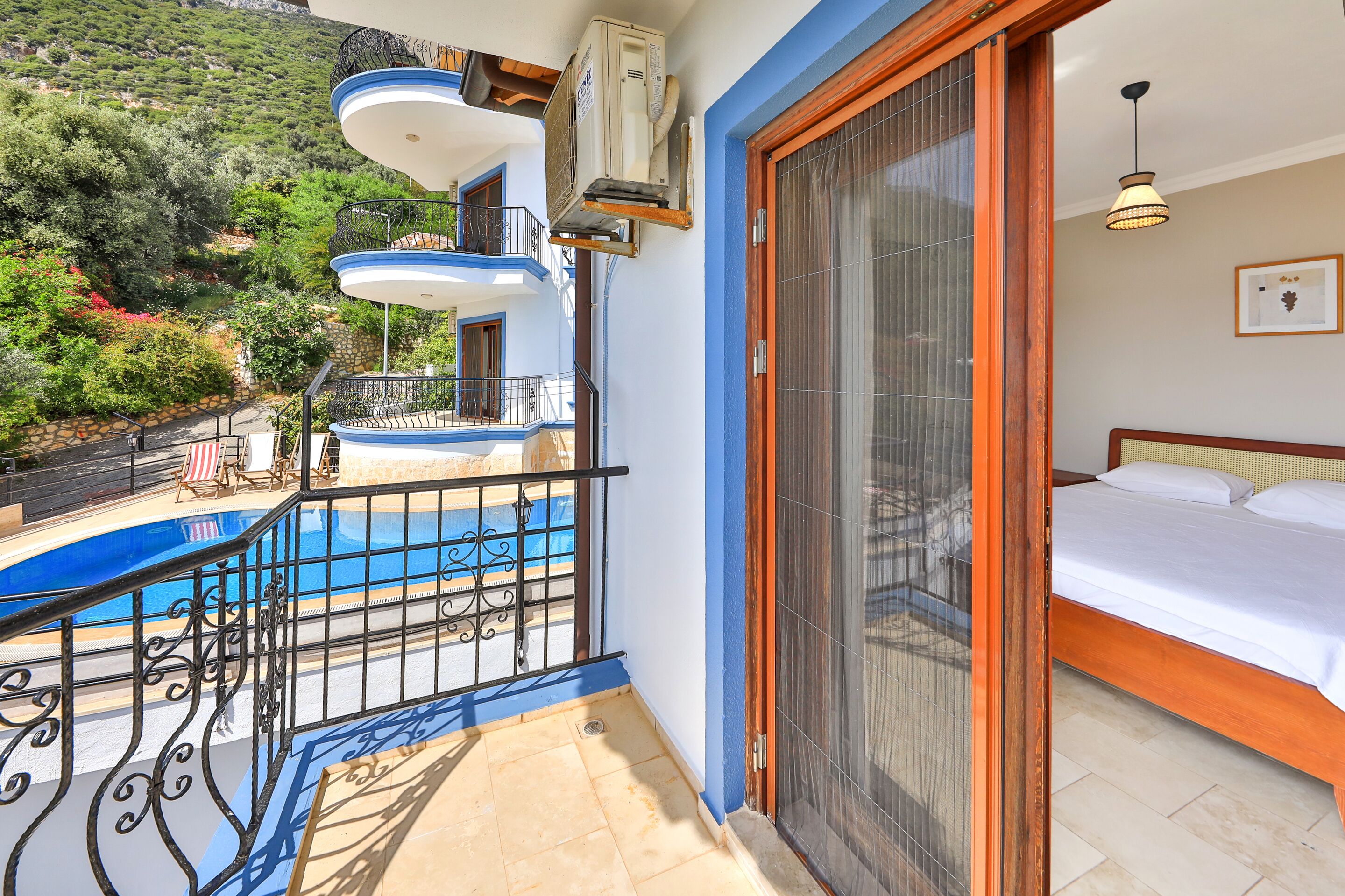 A balcony with a pool, a bed, and a view of a mountainous landscape.