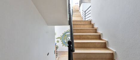 A staircase with beige steps and a black handrail, leading to an upper floor.