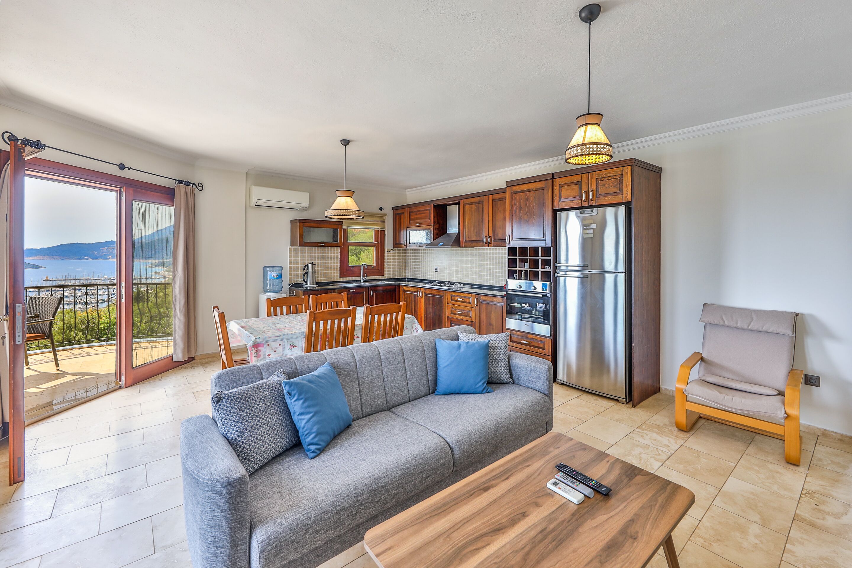 A modern kitchen with wooden cabinets, a stainless steel refrigerator, and a dining area with a table and chairs.