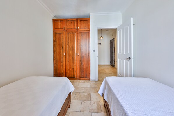A bedroom with two beds, wooden wardrobes, and a hallway leading to another room. - Nirvana Apart (Kas)