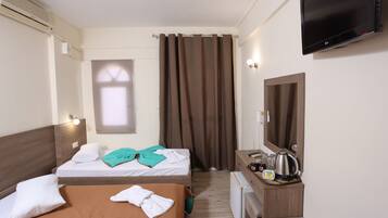 Camera d'albergo con due letti, televisione, angolo cottura e finestra con tende.