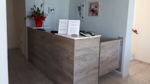A reception desk with a wooden finish, a potted plant, and a framed welcome sign. - Summer Beach Hotel (Kassandra)