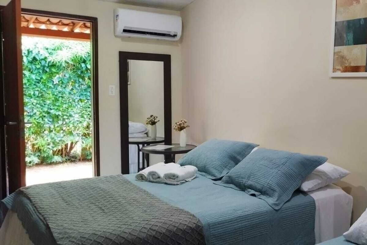 Ein Schlafzimmer mit einem Bett, einem kleinen Tisch mit Stuhl, einem Spiegel und einer Wand-Klimaanlage.