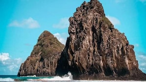 Un paysage côtier caractérisé par deux formations rocheuses imposantes et une plage de sable.