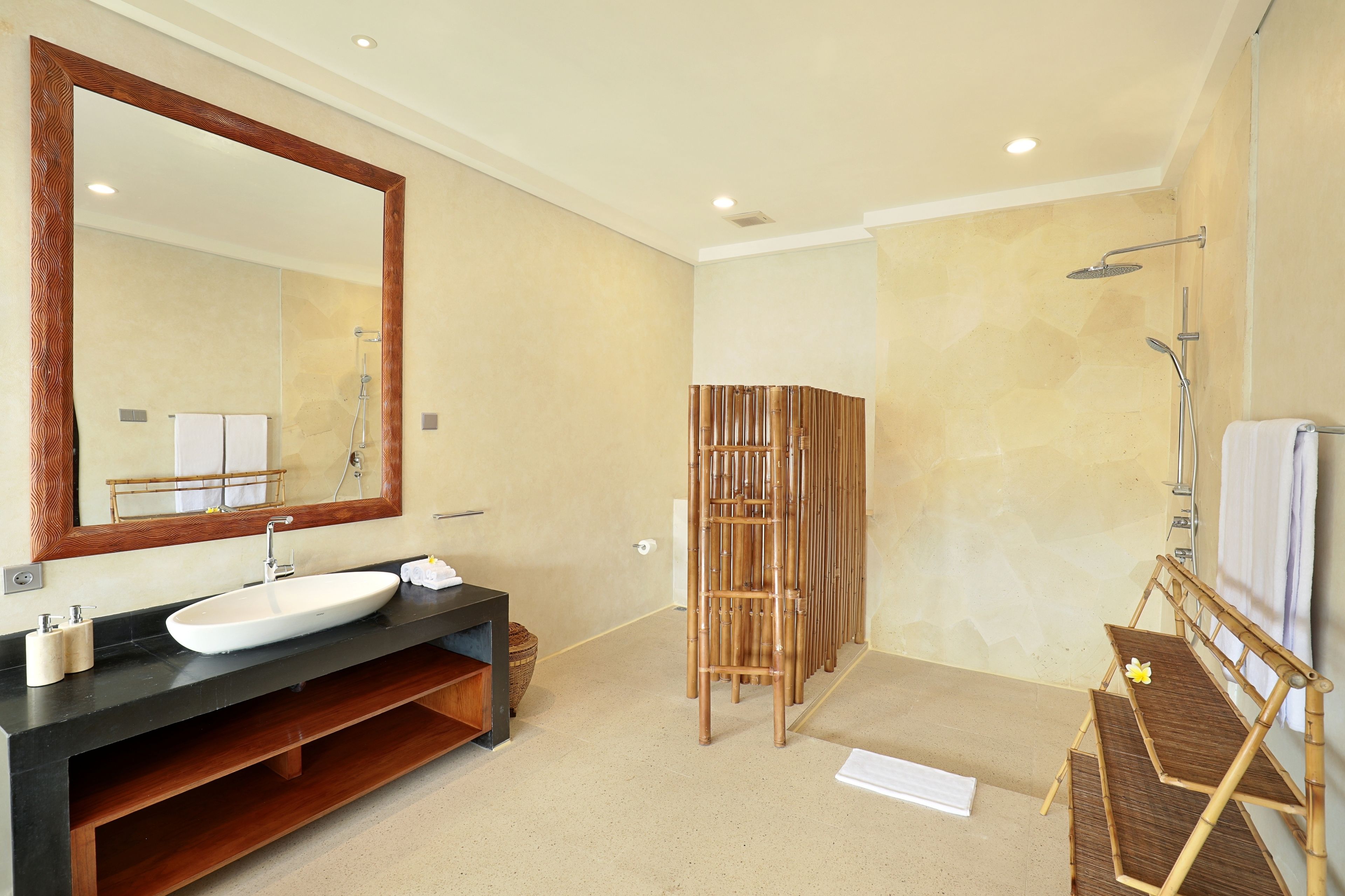 A modern bathroom with a large mirror, a sink, and a shower area.