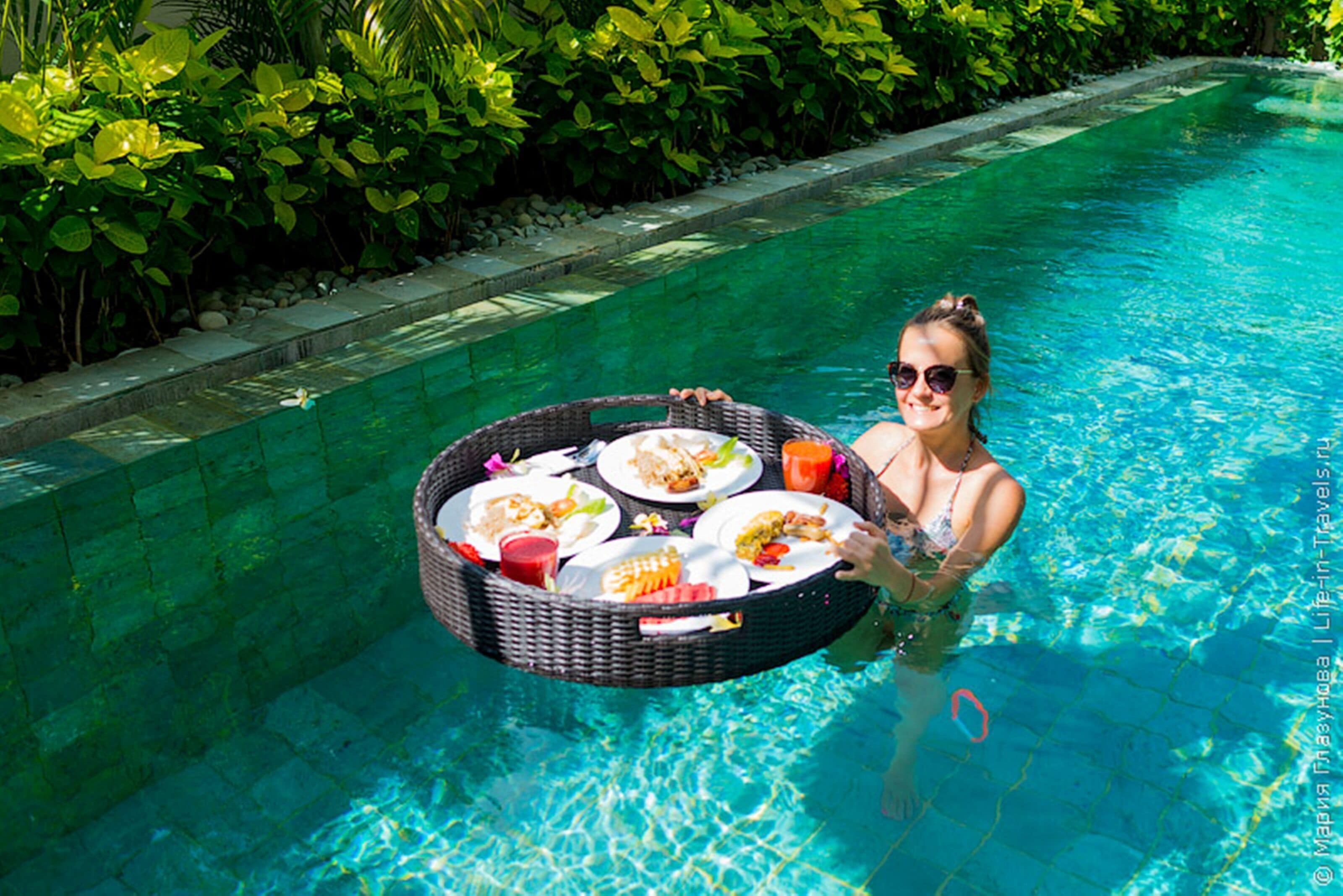 Una persona en una piscina sosteniendo una cesta con comida.