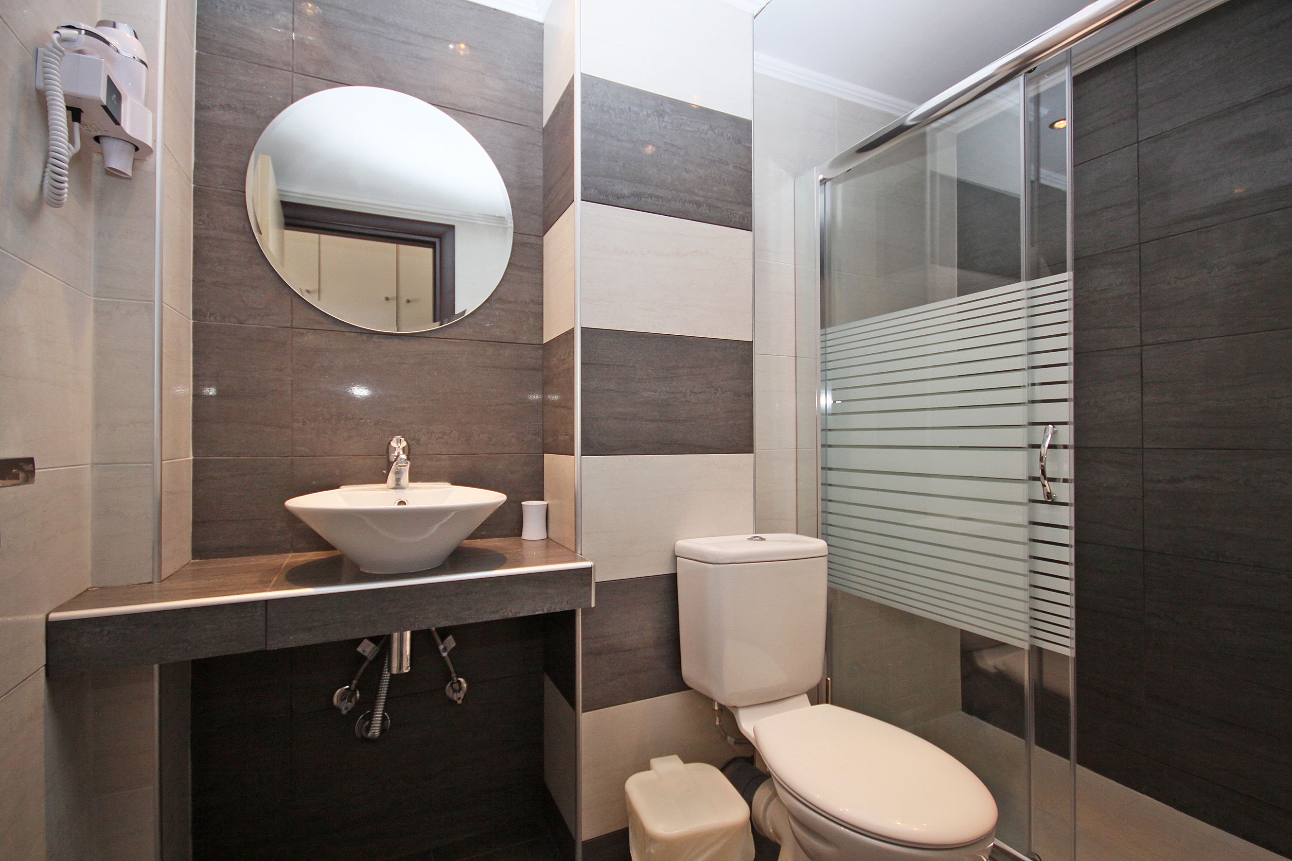 A modern bathroom with a sink, toilet, and a glass shower enclosure.
