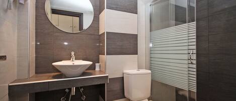 A modern bathroom with a sink, toilet, and a glass shower enclosure.