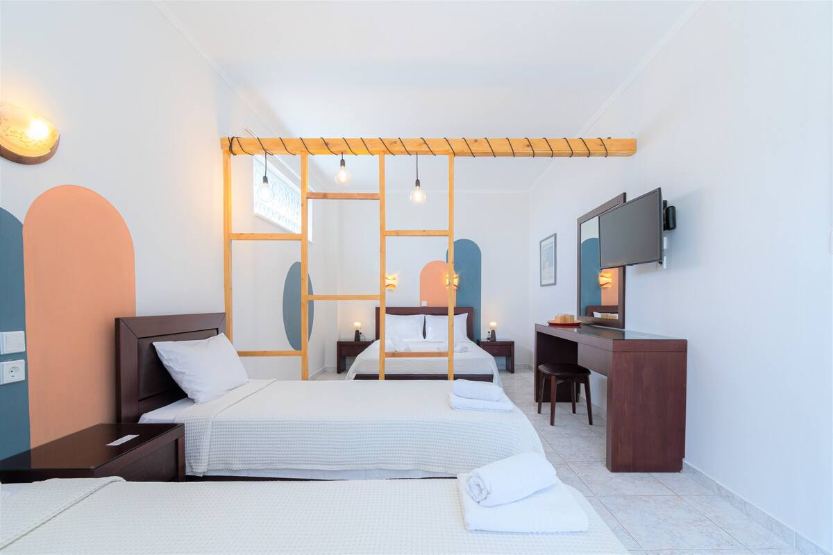 Ein modernes Hotelzimmer mit zwei Betten, einem Schreibtisch, einem Fernseher und einem großen Fenster.