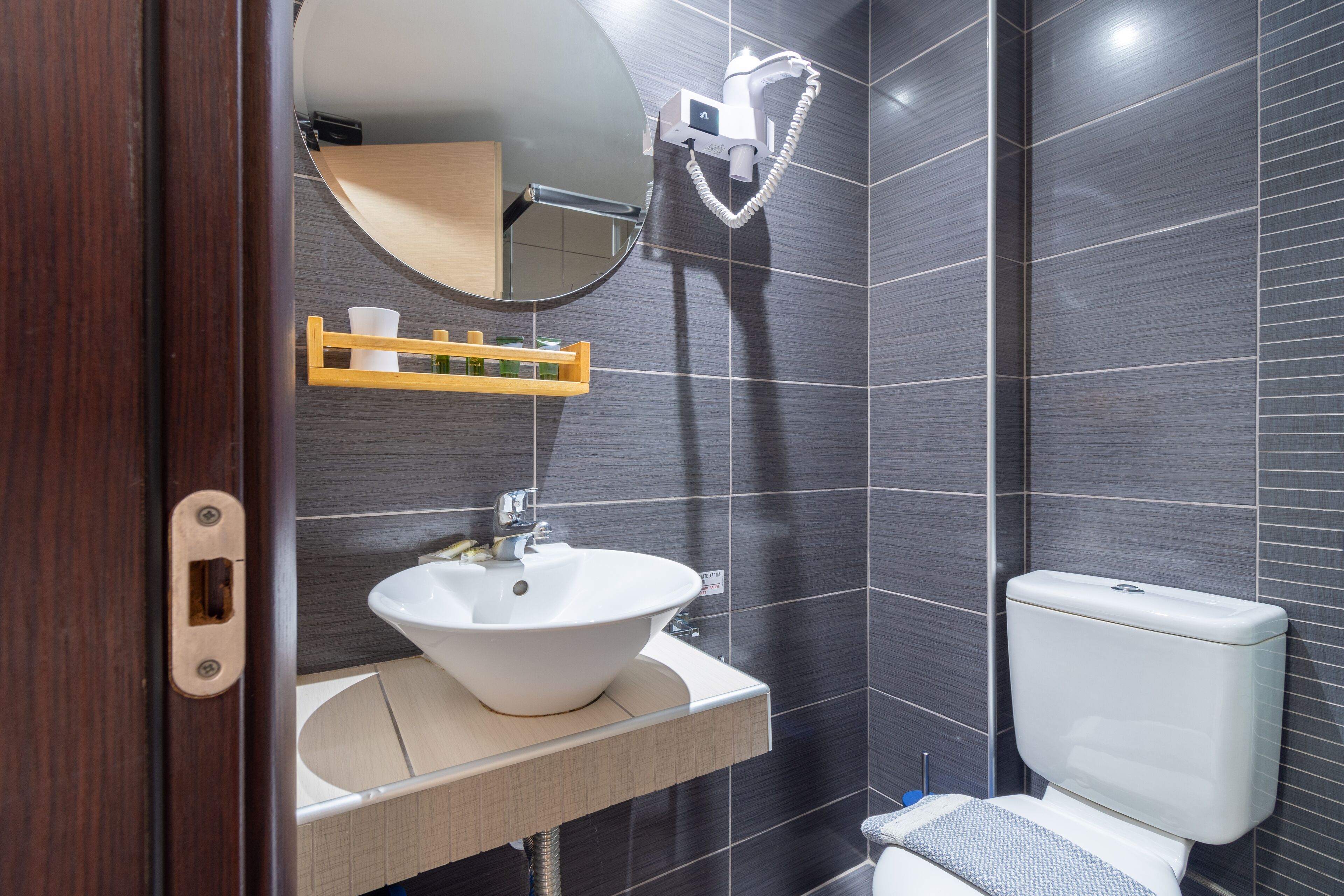 A modern bathroom with a white sink, a mirror, a toilet, and a shower head.