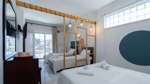 Quarto de hotel com duas camas, um separador de madeira, uma janela grande e vista para a cidade.