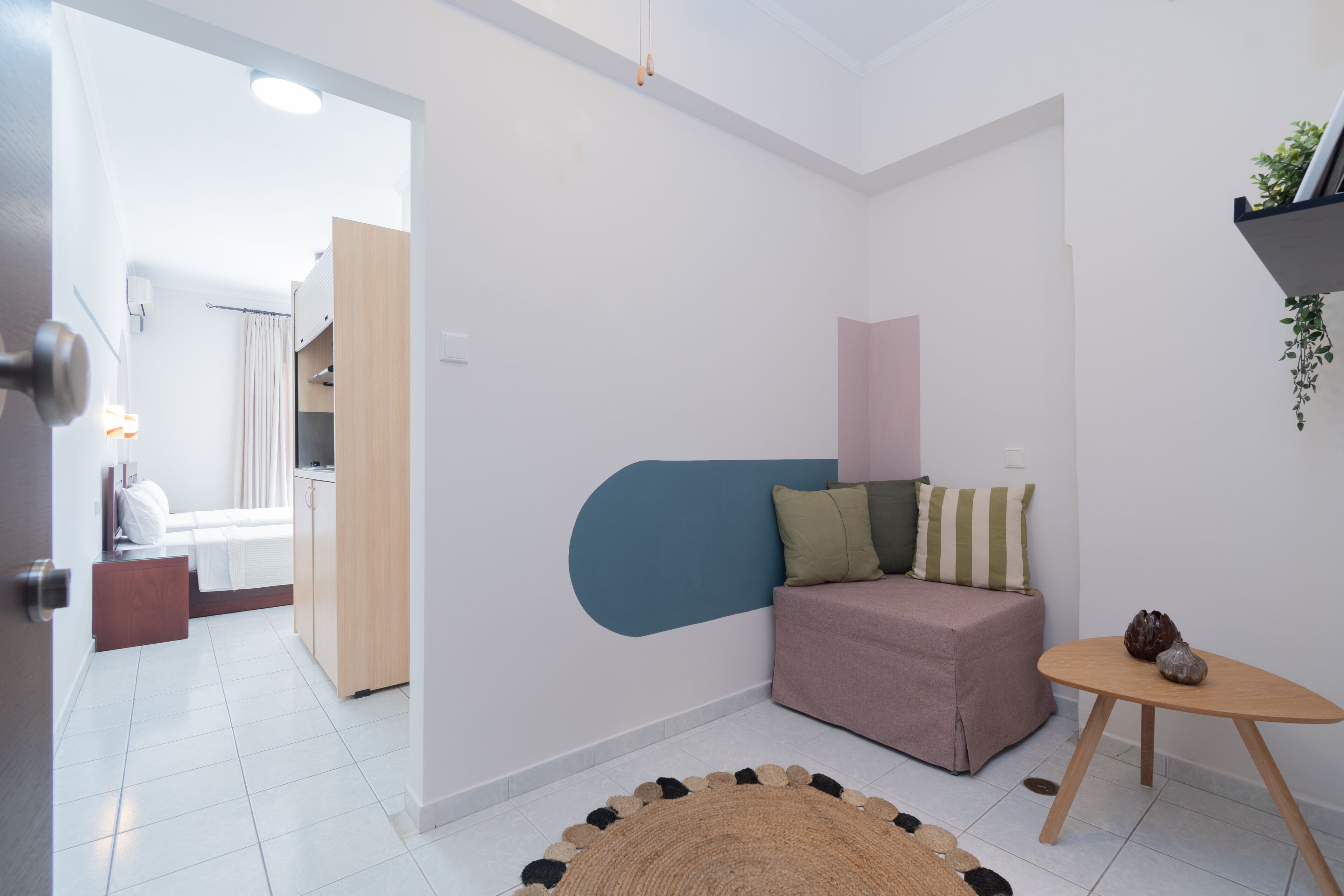 A modern, compact living space with a kitchenette, a sofa, a small table, and a decorative rug.