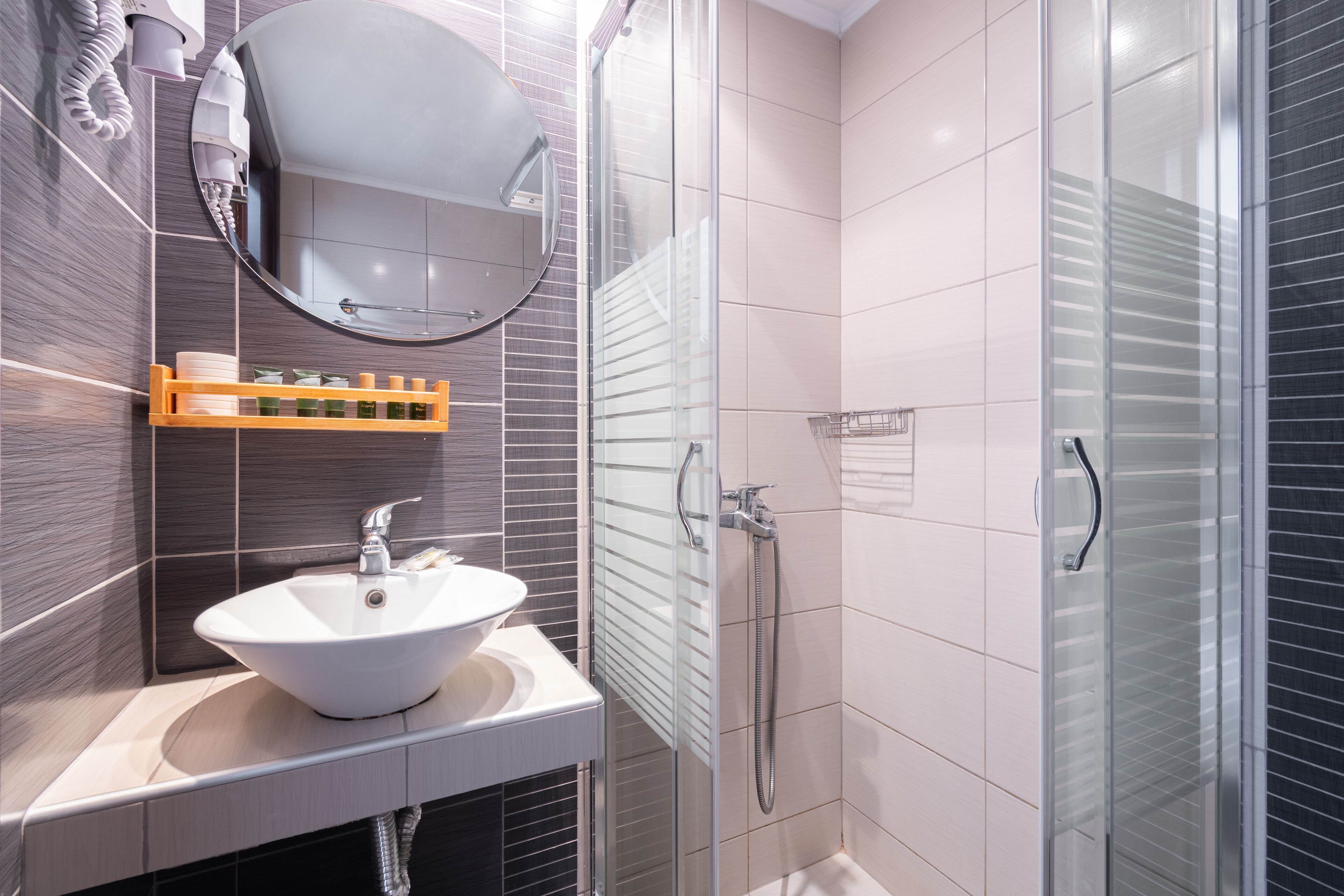 A modern bathroom with a white sink, a glass shower enclosure, and a mirror above the sink.