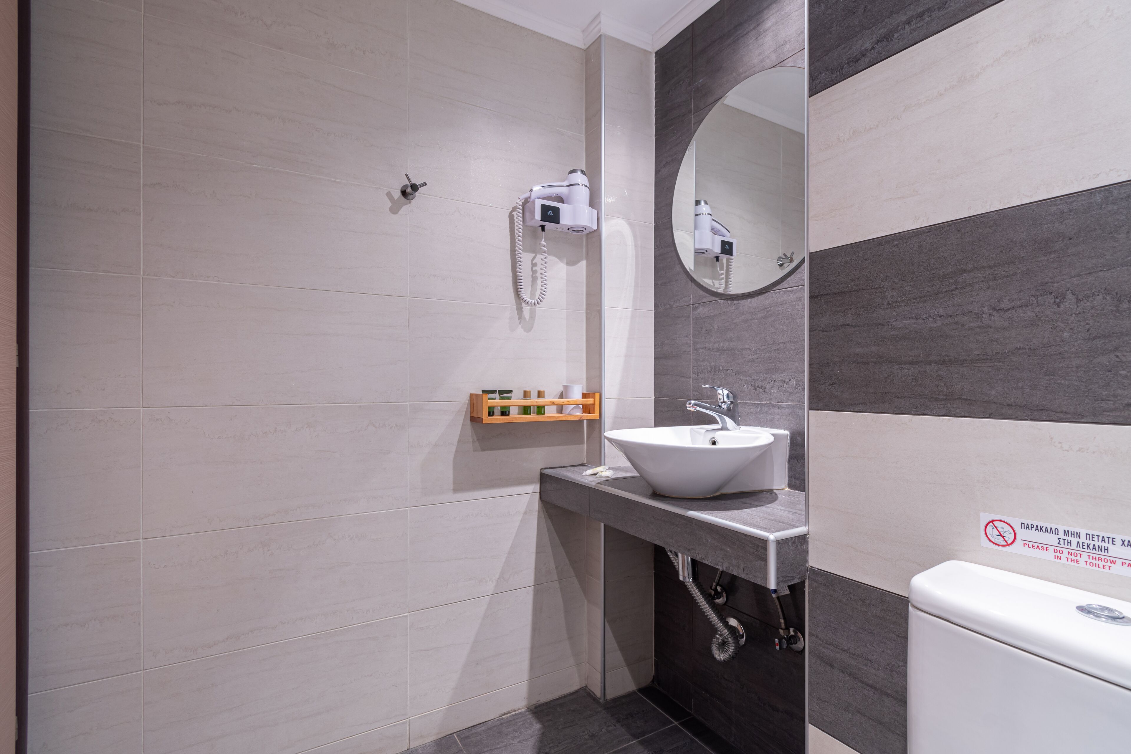 Un baño moderno con ducha, lavamanos e inodoro. Hay un perchero y un espejo.