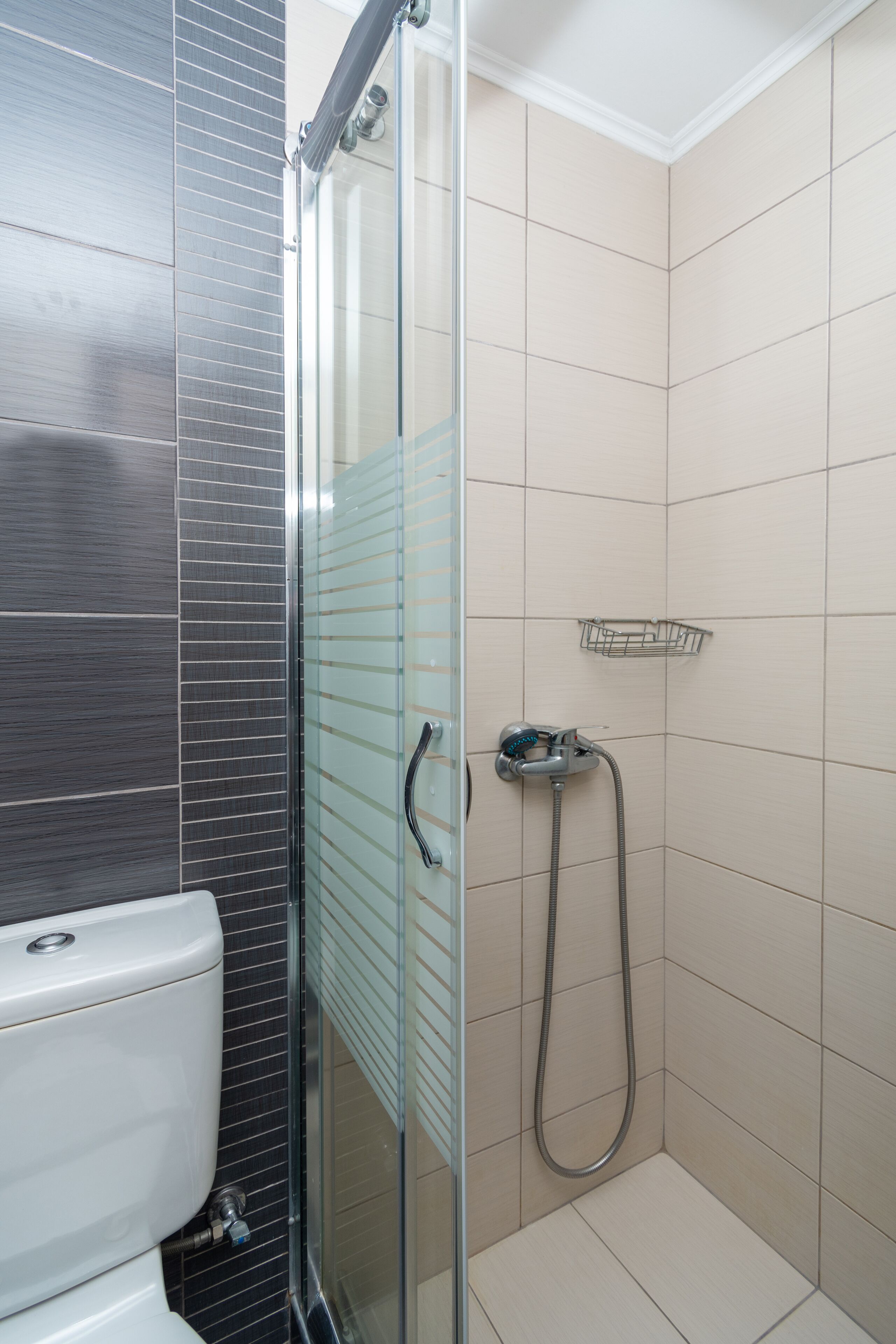 Un baño con ducha de vidrio, inodoro y paredes de azulejos.