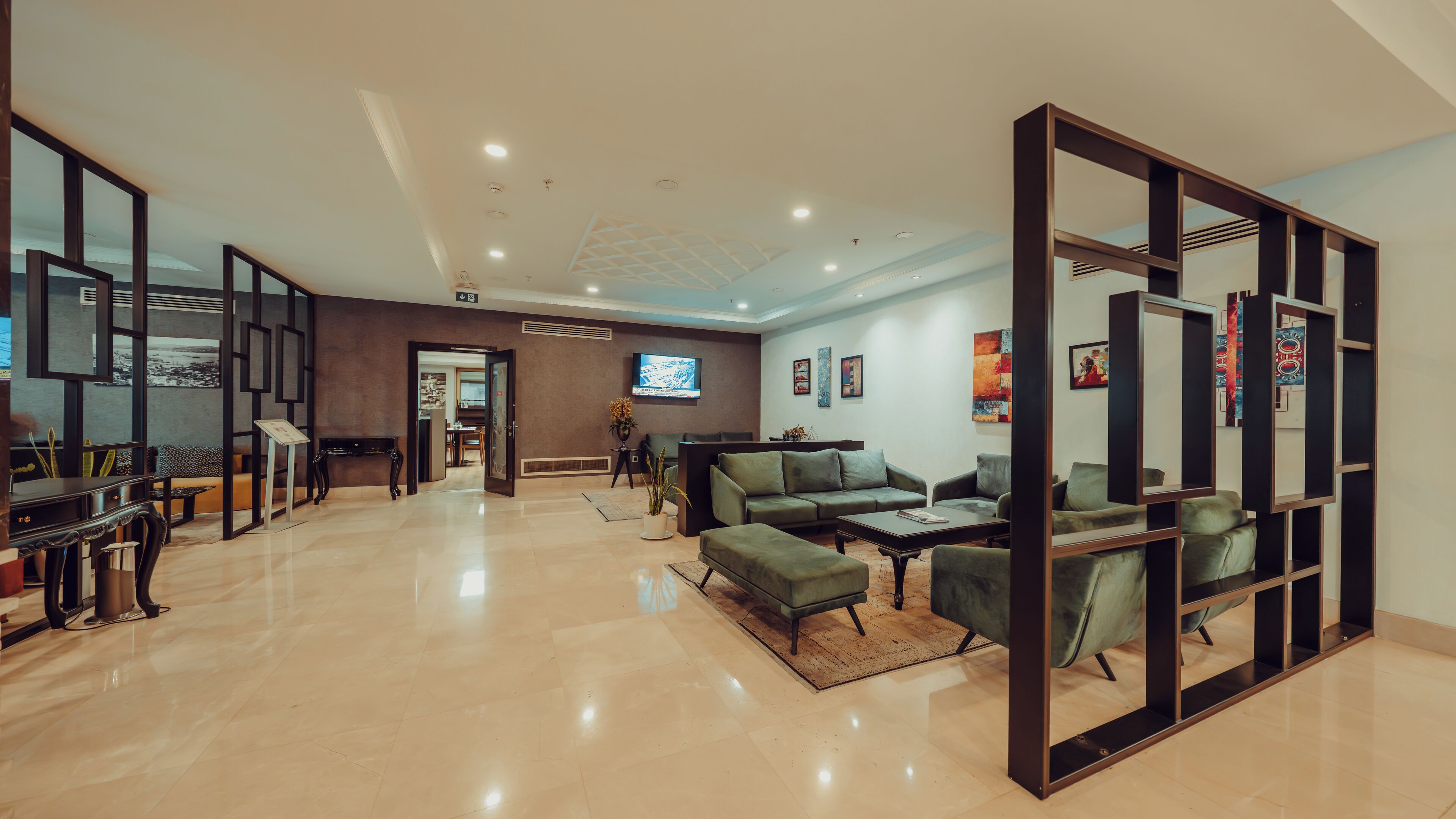 A spacious lobby with a reception desk, seating area, and a television.