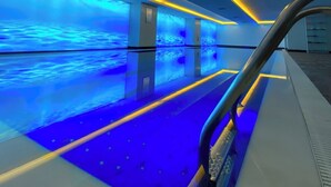 Ein moderner, überdachter Pool mit blauer Beleuchtung und gelben Akzenten.