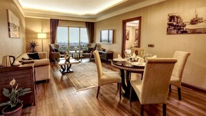 Amplia sala de estar con una gran mesa de comedor, asientos cómodos, un televisor y vistas a la ciudad.